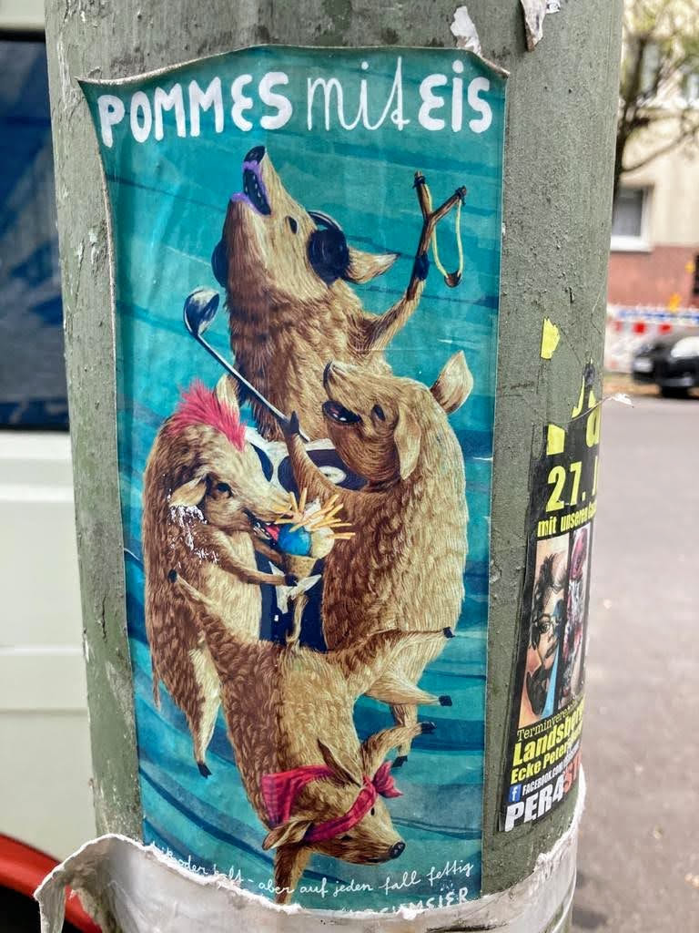 The central sticker features three anthropomorphic wild boars against a vibrant teal/turquoise background with subtle horizontal stripes. The top boar wears black headphones, looking upwards with an open mouth as if singing or howling, and holds a wooden slingshot. The middle boar holds a silver golf club, appearing to serve or mix a blue and yellow concoction (likely 'pommes' and 'eis') in a small bowl. The bottom boar, wearing a red patterned bandana around its neck, is depicted in a dynamic, possibly dancing, pose. All boars have brown fur with detailed textures. The overall style is illustrative and whimsical, depicting a lively, humorous scene.
