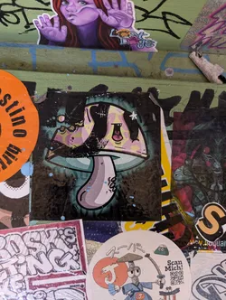 Funky, trippy sticker of a mushroom with a teal and pink color scheme. The style is reminiscent of graffiti art, with bold outlines and a slightly distressed look. The mushroom has a happy, almost cartoonish expression.