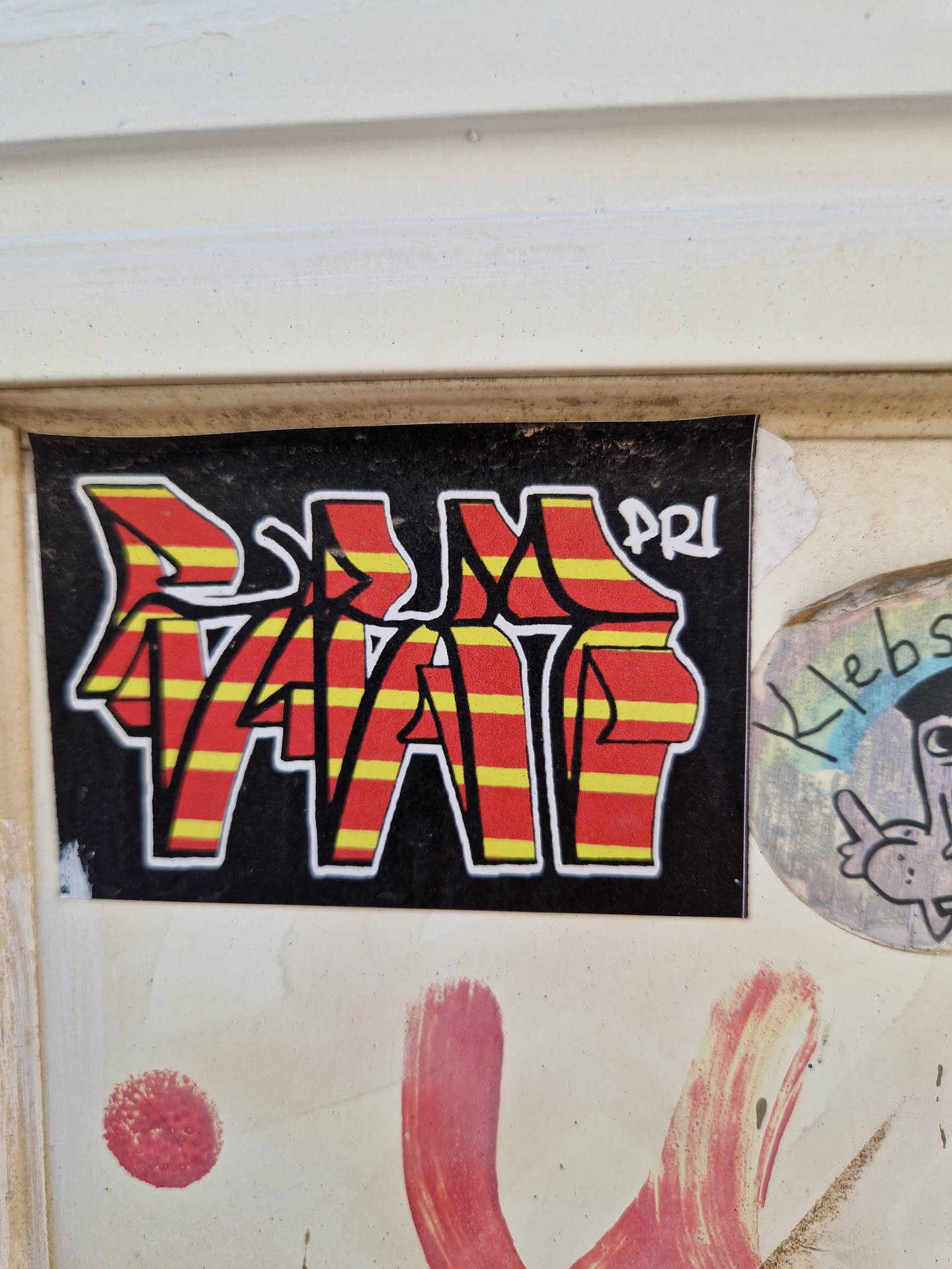 A sticker with a bold graffiti-style design. The letters "VAP" are prominently displayed in red and yellow striped lettering on a black background.  A smaller, less distinct "PRI" appears near the top right corner. The style suggests street art or graffiti influence.
