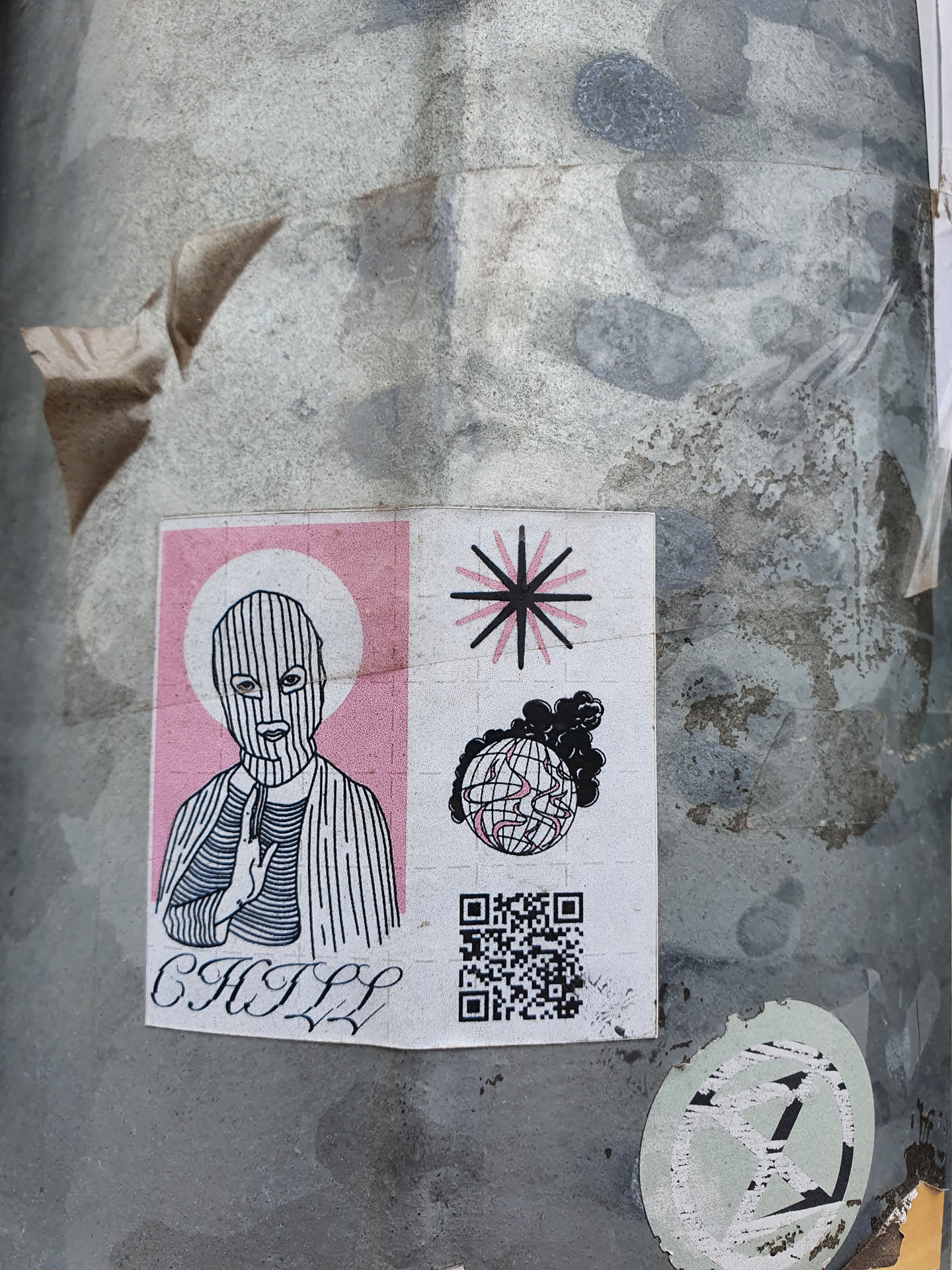 A sticker featuring a stylized illustration of a person wearing a balaclava, making a gesture resembling prayer or meditation.  The background features a pink panel and symbols including a starburst and a burning globe. A QR code is present at the bottom.