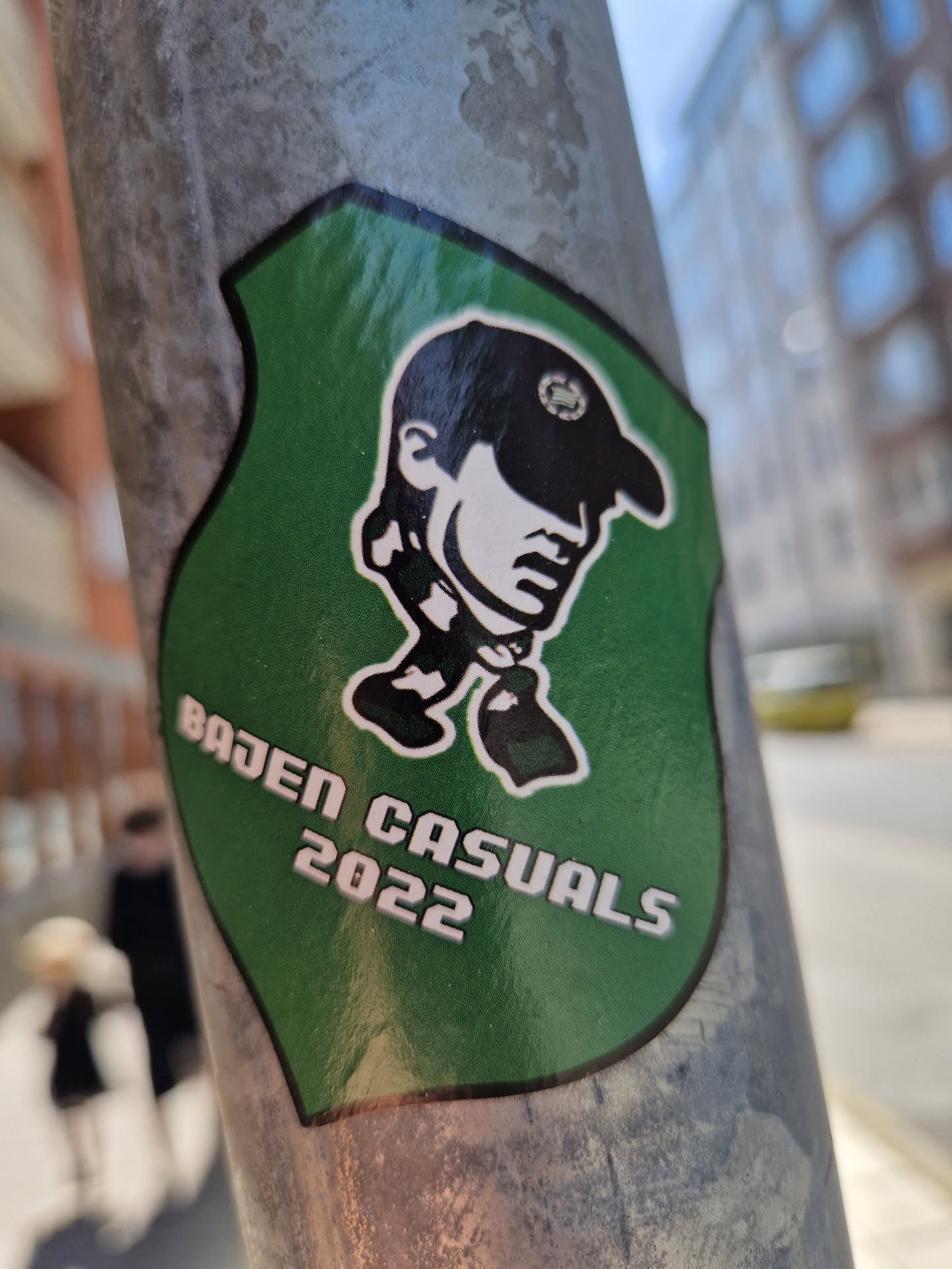Green sticker with a cartoon illustration of a person wearing a cap. The text 'Baden Casuals 2022' is visible on the sticker.