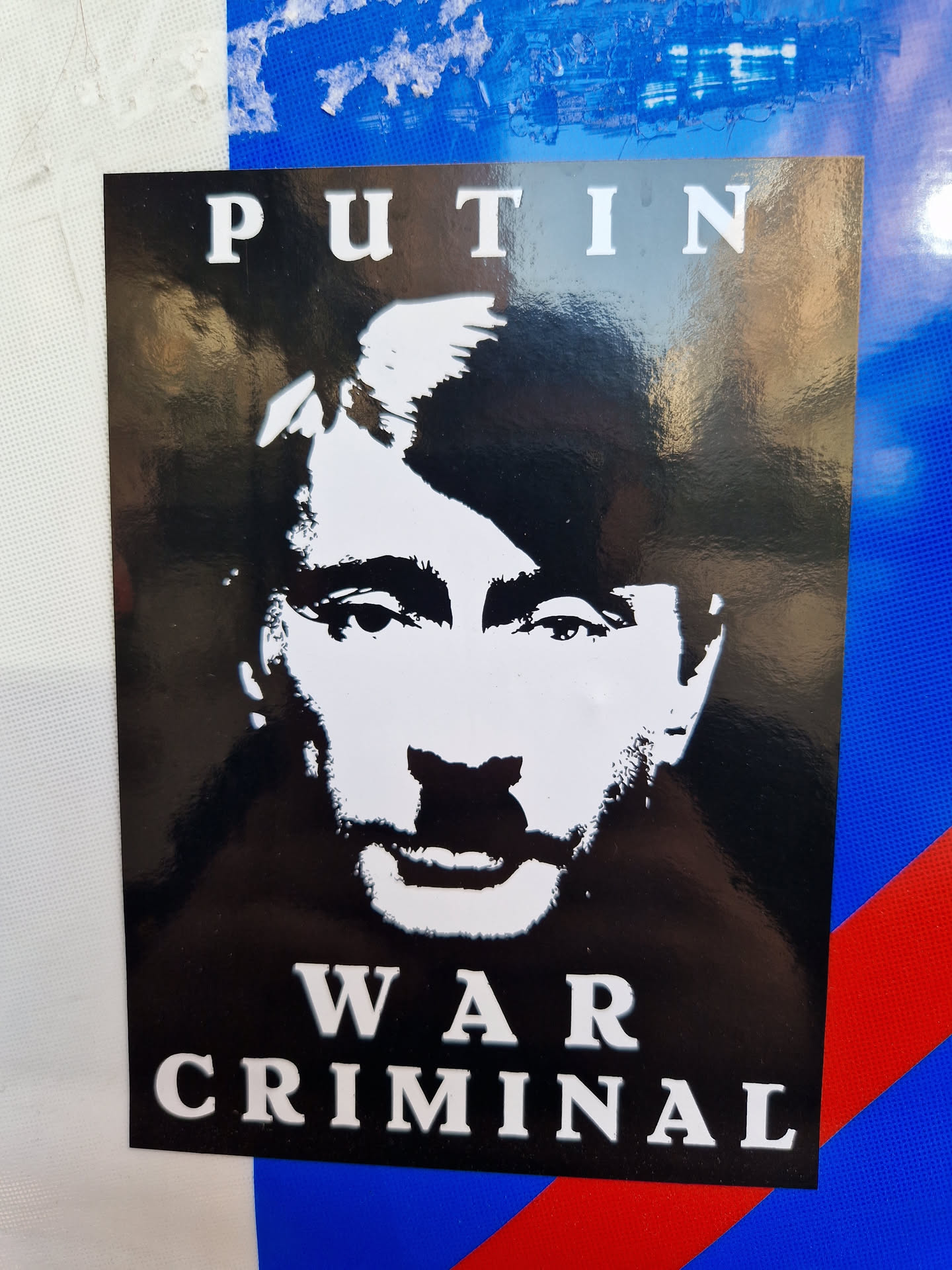 Black and white sticker depicting Vladimir Putin with the text 'PUTIN' above his image and 'WAR CRIMINAL' below.