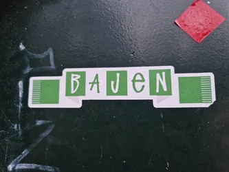 A sticker featuring the German word 'BAUEN' (meaning 'to build') in a simple, stylized design. The text is white against a green background and looks like a banner.  The green end pieces have white vertical lines. 