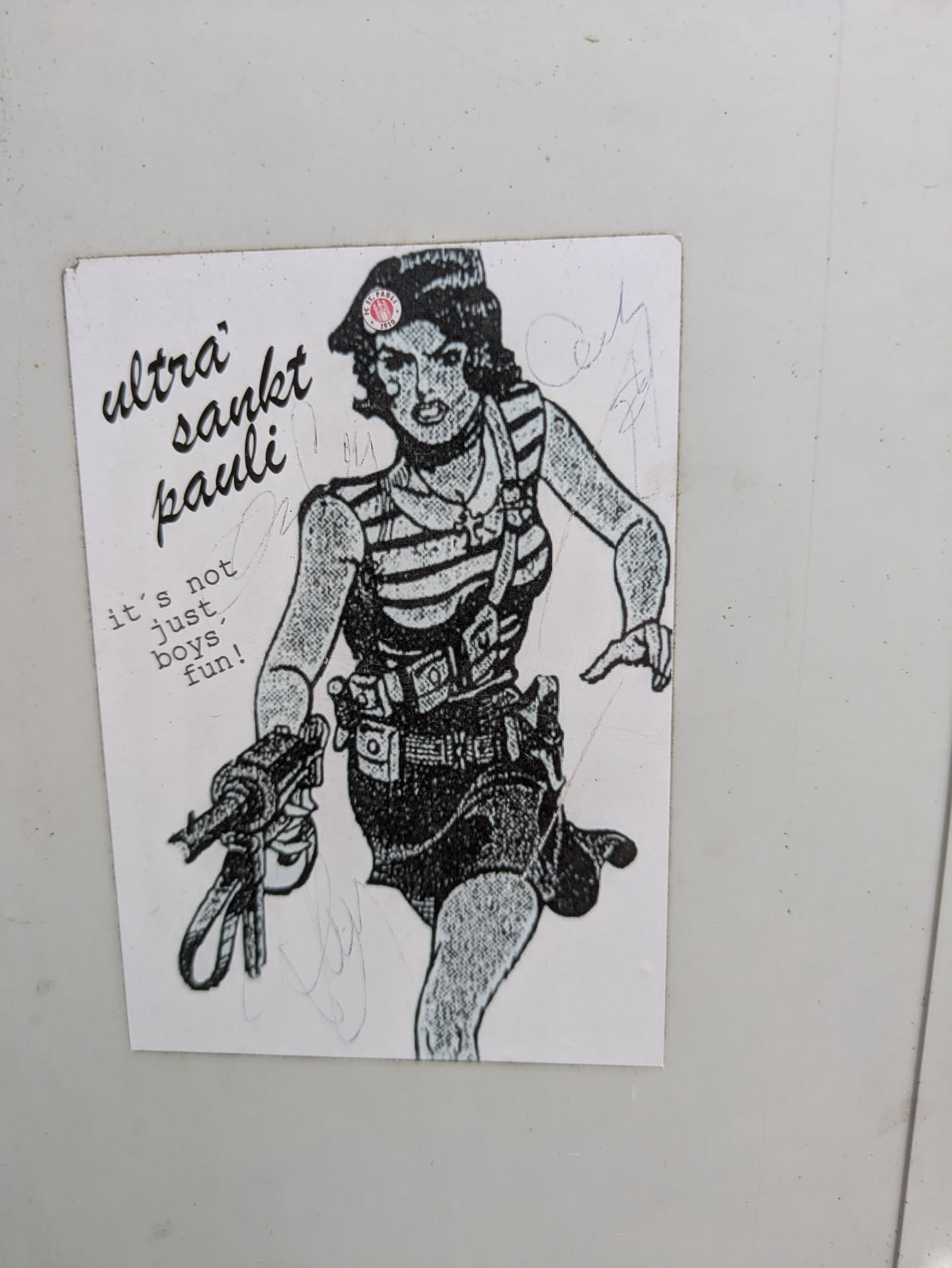 This sticker features a drawing of a woman wearing a striped shirt and a beret with a St. Pauli logo on it. She is holding a gun and has other equipment strapped to her. The text on the sticker says "Ultra Sankt Pauli" and "it's not just boys fun!".