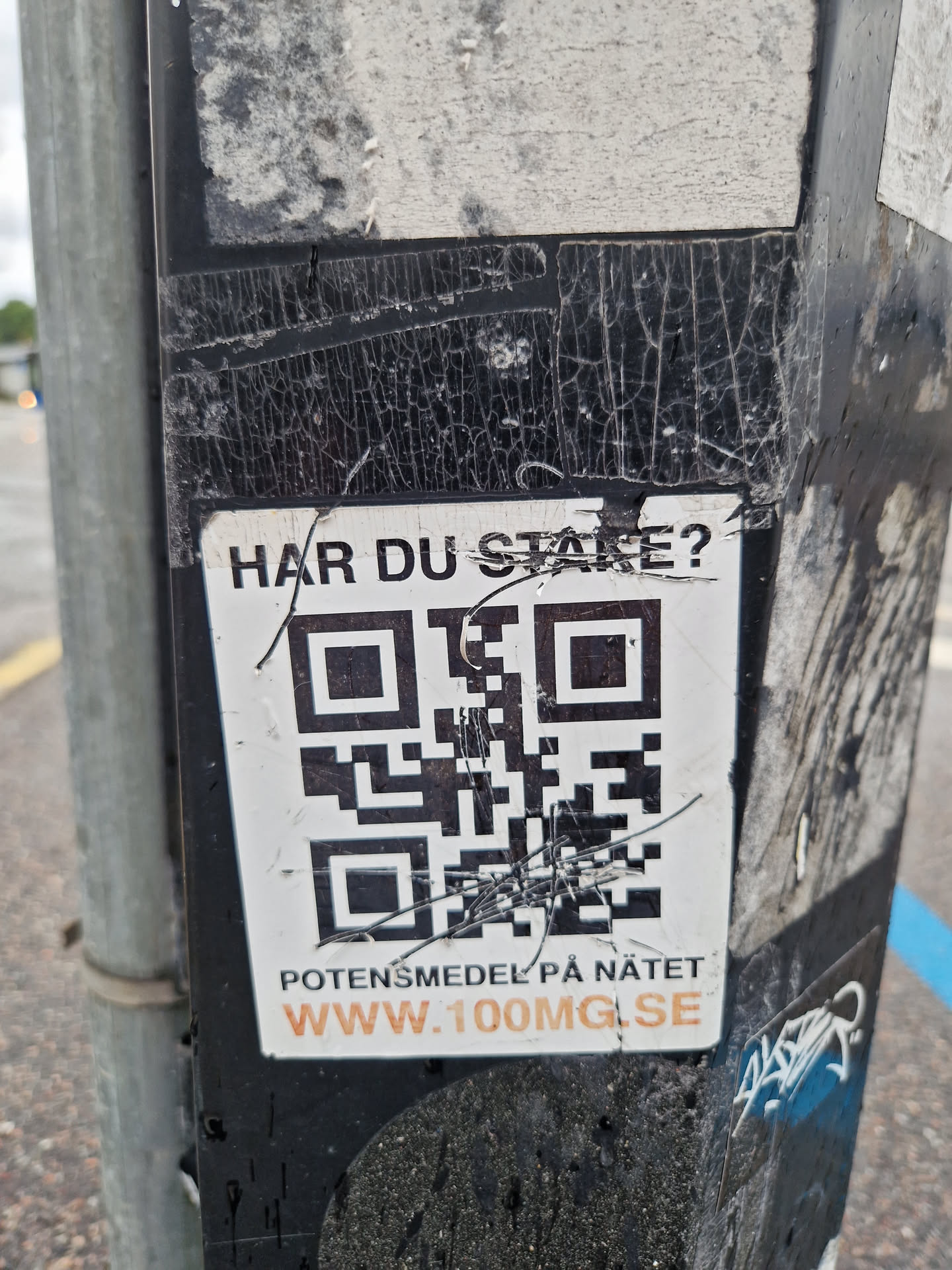 A worn sticker with a QR code and text in Swedish. The text translates to: "Do you stare? Potency drugs online www.100mg.se"