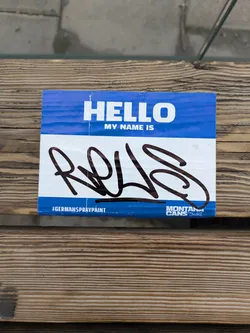 A blue name tag sticker with the text 'HELLO MY NAME IS' and a graffiti signature 'RQLS'. The sticker also features the logos for German Spray Paint and Montana Cans.