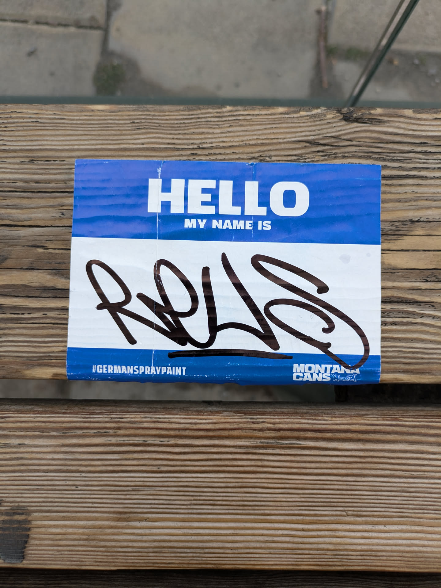 A blue name tag sticker with the text 'HELLO MY NAME IS' and a graffiti signature 'RQLS'. The sticker also features the logos for German Spray Paint and Montana Cans.