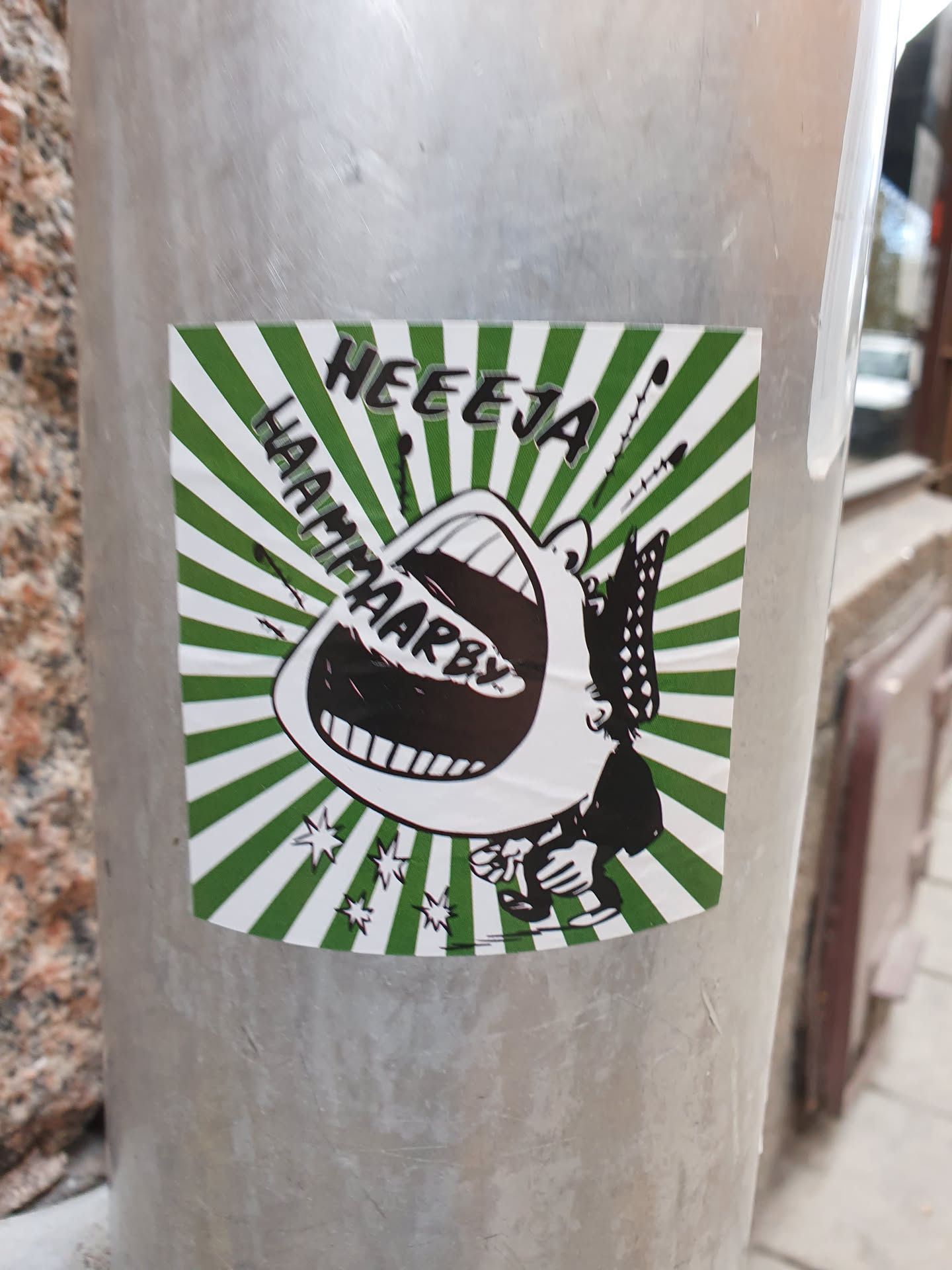 A sticker featuring a cartoon illustration of a large mouth with the text "HEEEJA HAAMPAARBY!" in a green and white sunburst design. The style is reminiscent of vintage comics or pop art.