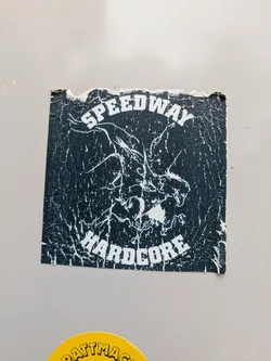 A black and white square sticker with the text "SPEEDWAY" on the top and "HARDCORE" on the bottom. There is an illustration of what appears to be a dragon head between the text.