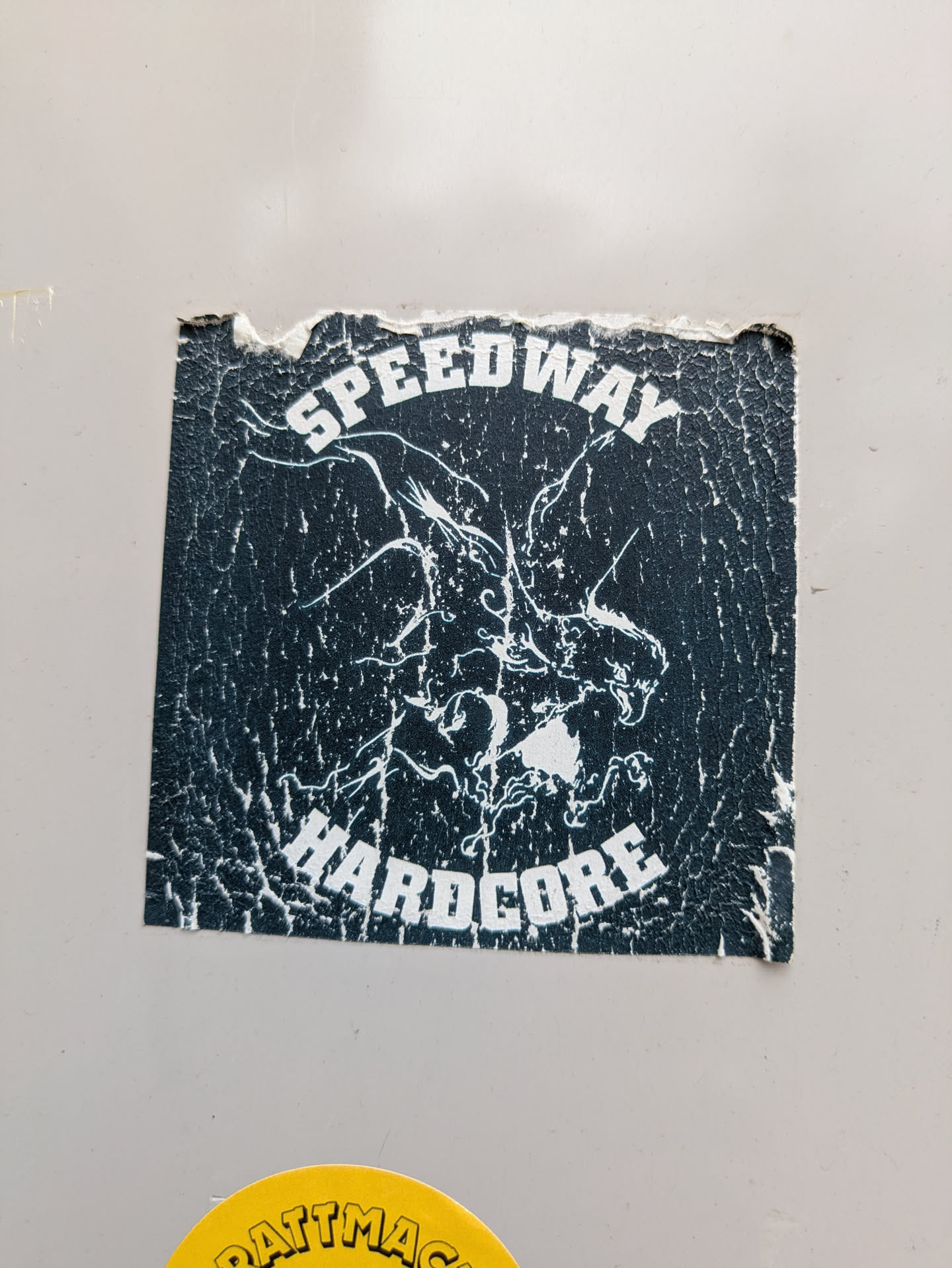 A black and white square sticker with the text "SPEEDWAY" on the top and "HARDCORE" on the bottom. There is an illustration of what appears to be a dragon head between the text.