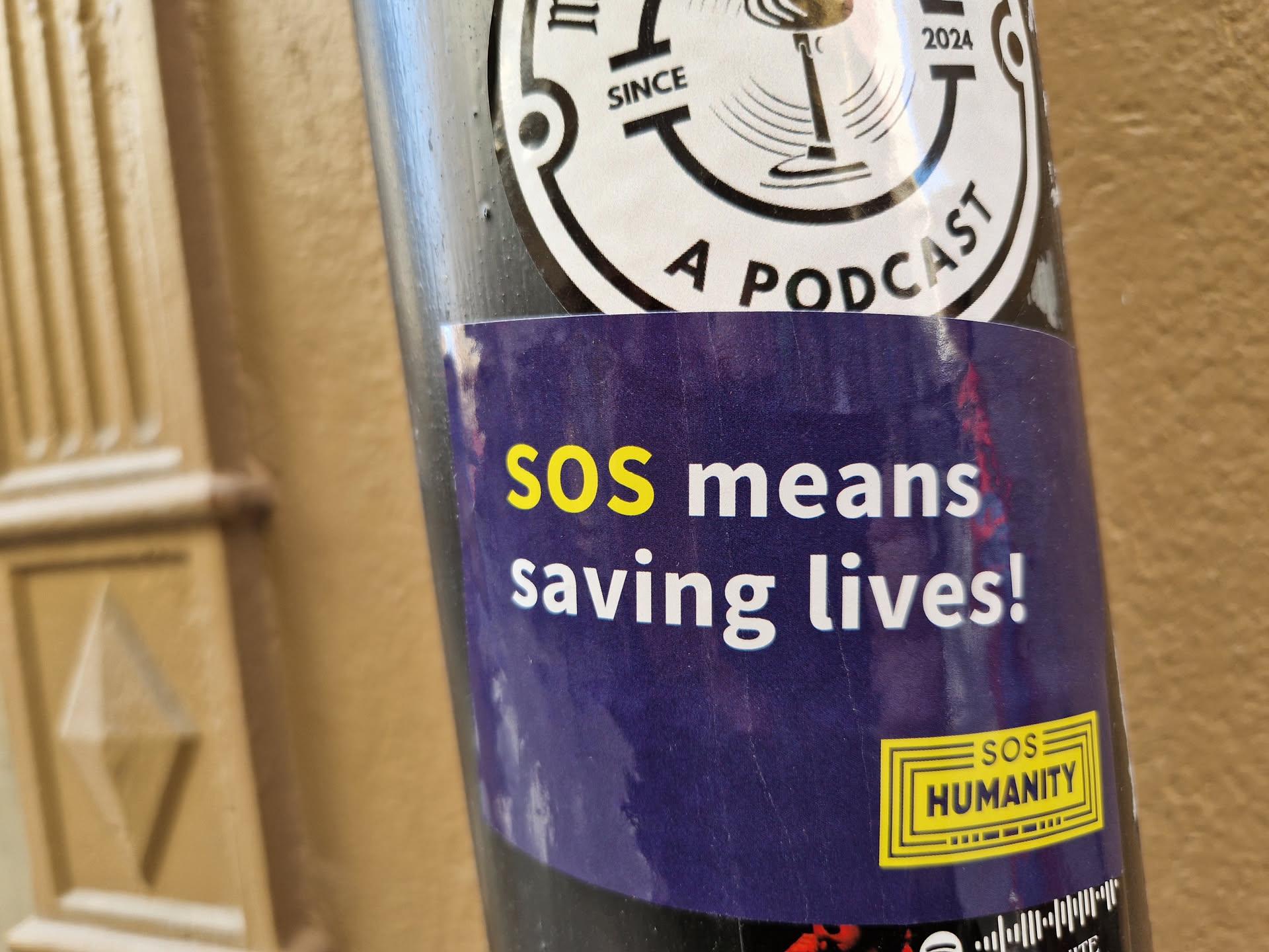 A dark purple sticker with the text "SOS means saving lives!" in yellow.  It also has a small yellow box with the text "SOS Humanity".