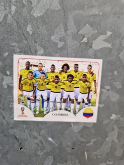 A sticker featuring the Colombian national football team. The players are wearing their yellow and blue uniforms.  The sticker includes the team name and the Colombian flag.
