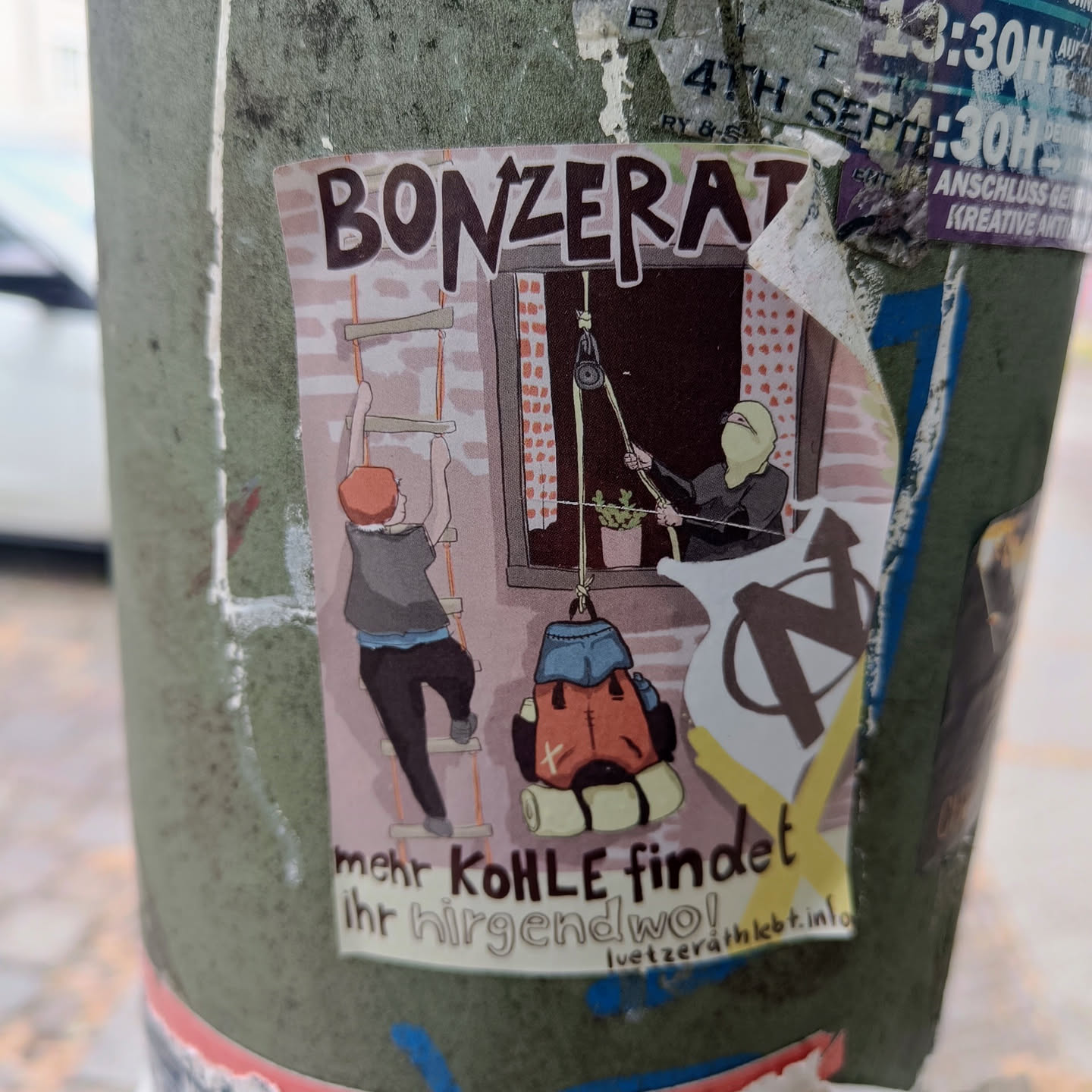 A sticker depicting an illustration of two people climbing a ladder and lowering a backpack with the word "Bonzerat" and the phrase "More coal can be found somewhere!" The sticker also features an anarchist symbol. The website luetzerathlebt.info is mentioned at the bottom. 