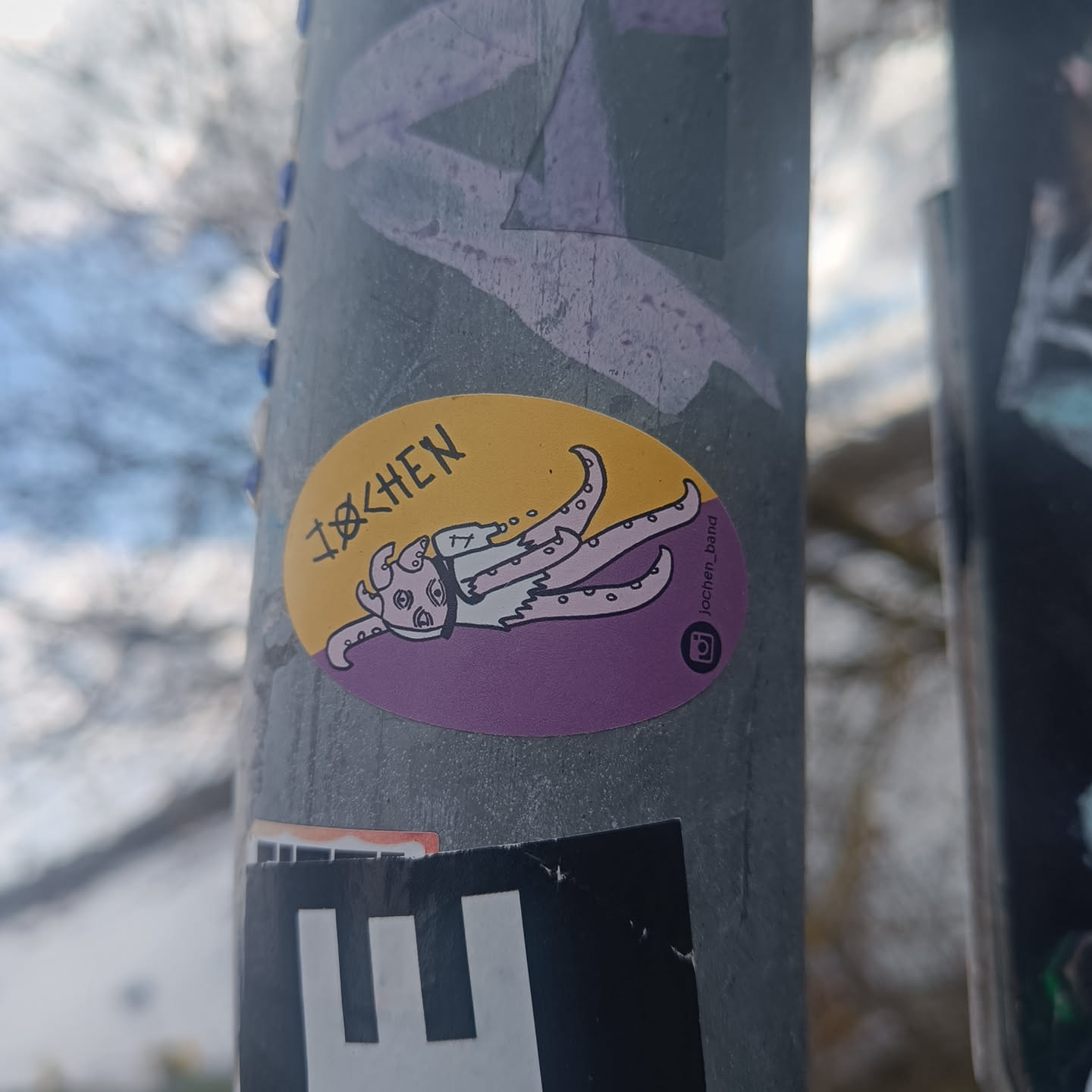 Oval sticker featuring an illustration of a cute yet creepy octopus-like creature. The sticker has a purple and yellow color scheme. The text "IOCHEN" is visible at the top, along with an Instagram logo and the artist's handle: Iochen_Drawing.