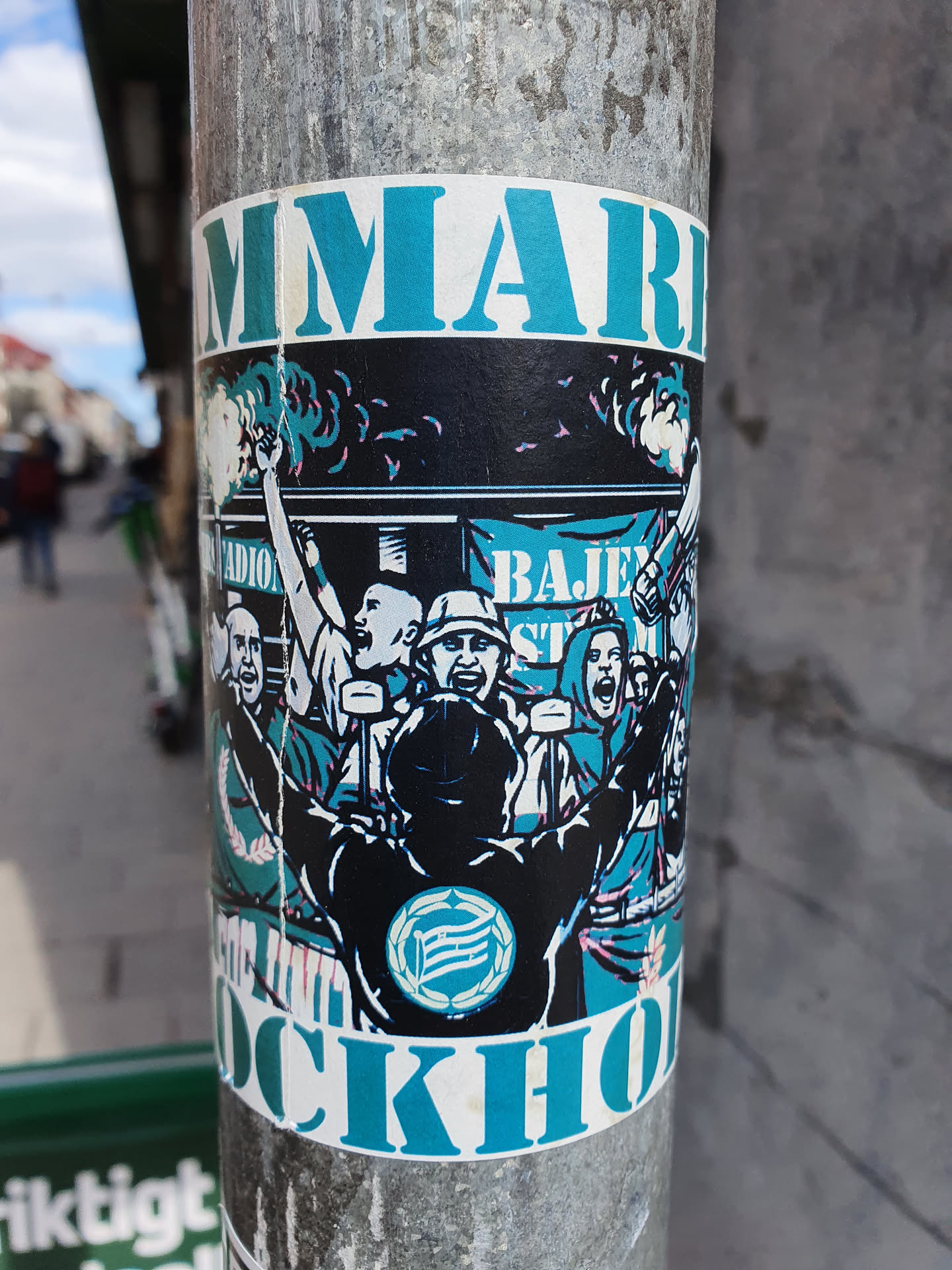 A sticker depicting a lively scene of Hammarby Stockholm supporters celebrating. The illustration showcases a group of enthusiastic fans, arms raised in jubilation, against a backdrop suggesting a stadium atmosphere. The colors are predominantly teal and black, with the words "HAMMARBY" and "STOCKHOLM" prominently displayed, creating a visually striking and dynamic image.