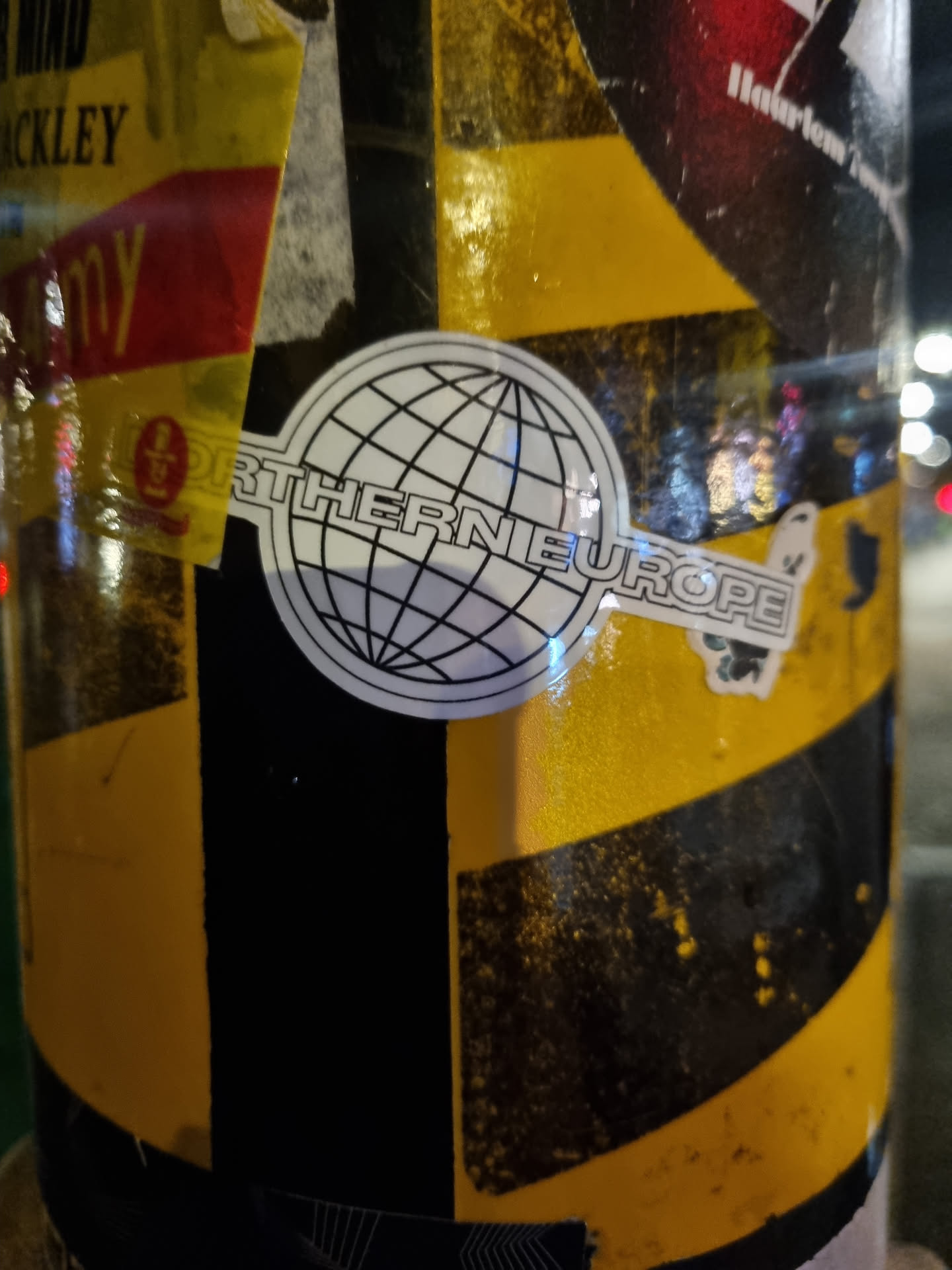 A black and white sticker with an image of a globe and the words "Northern Europe" printed around it. The sticker is on a yellow and black striped surface. 
