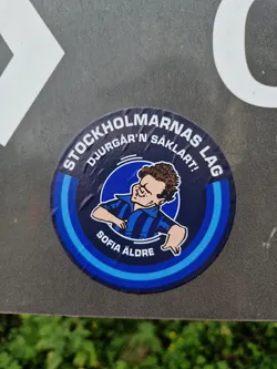 Round sticker featuring a cartoon illustration of a man in a blue and black striped shirt. The text on the sticker says "Stockholmarnas lag" which translates to "Stockholm's team", "Djurgården" and "Säklart!" which means "Of course!" in Swedish.  There is also the text "Sofia äldre" at the bottom.