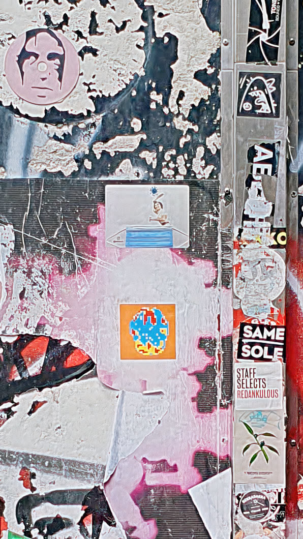 A square sticker with a orange background features a blue and red pixelated globe in the center. It's part of a collection of stickers adhered to a weathered wall.