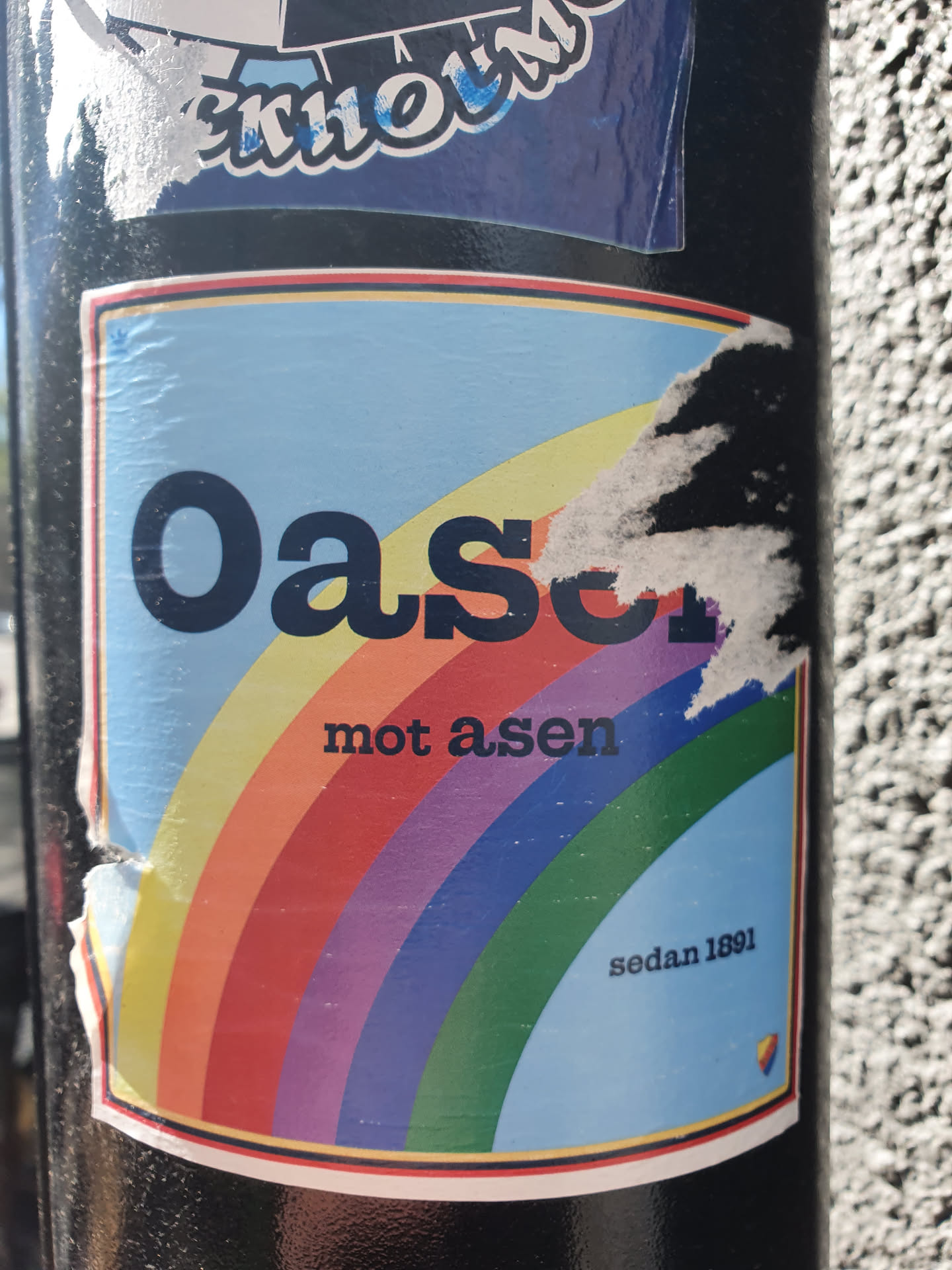 A sticker with a rainbow and the text "Oasis mot asen sedan 1891".