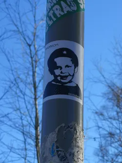 A rectangular, white sticker featuring a high-contrast black and white graphic of a smiling baby's head and shoulders. The baby has a wide grin and is wearing a dark cap adorned with a prominent white five-pointed star on the front. Above the baby's head, the word 'BADDABOOM' is written in a stylized, slightly distressed font. Below the baby's shoulders, the word 'BADDABING' is written in a similar font. The overall style is reminiscent of stencil art or a simplified graphic design.