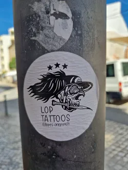 A black and white sticker featuring a skull with a dagger, three stars, and the text "LOP TATTOOS @lopes_onepunch".