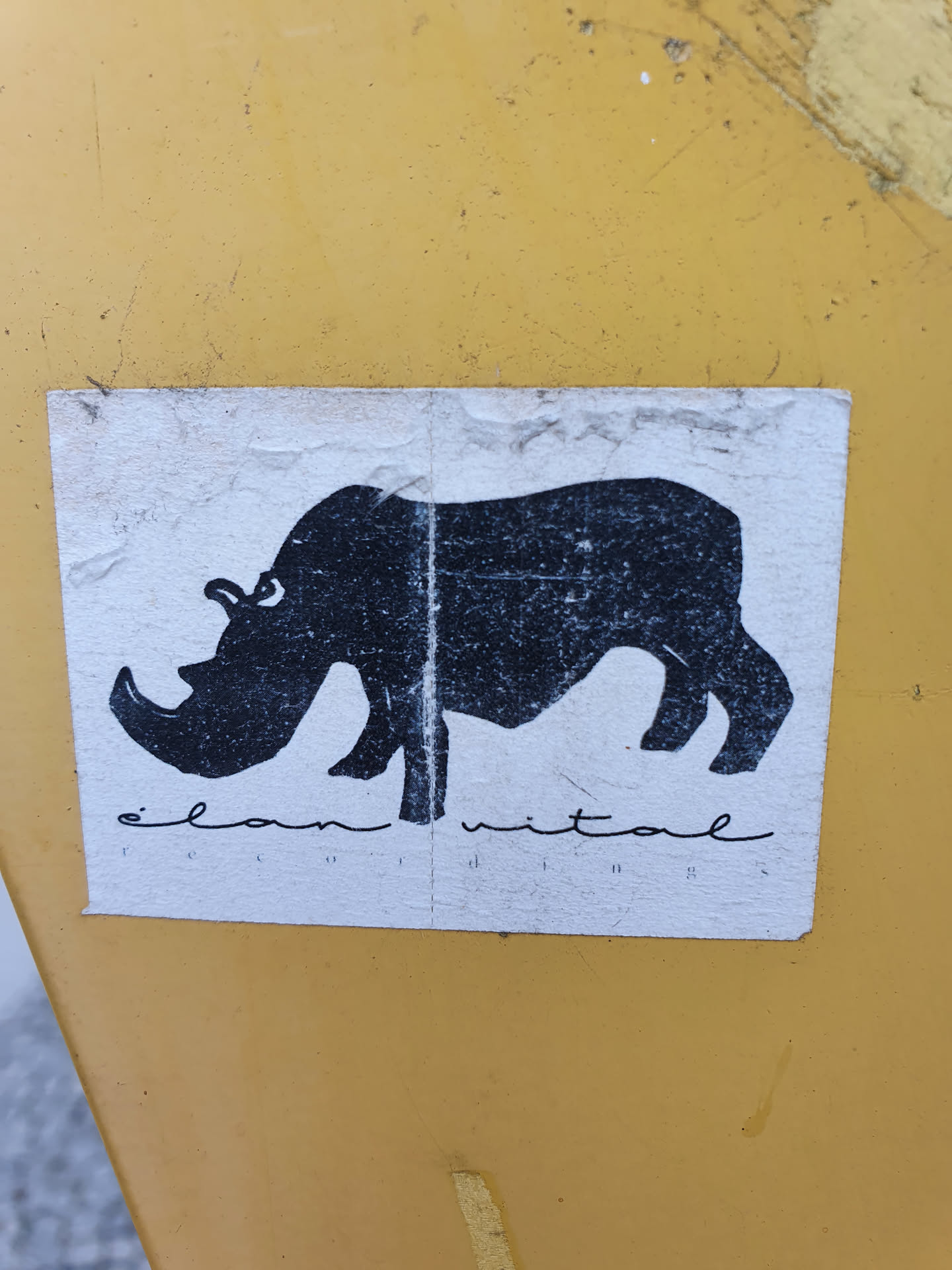 A sticker featuring a simple black silhouette of a rhinoceros.  The text 'elan vital' is printed beneath the image.