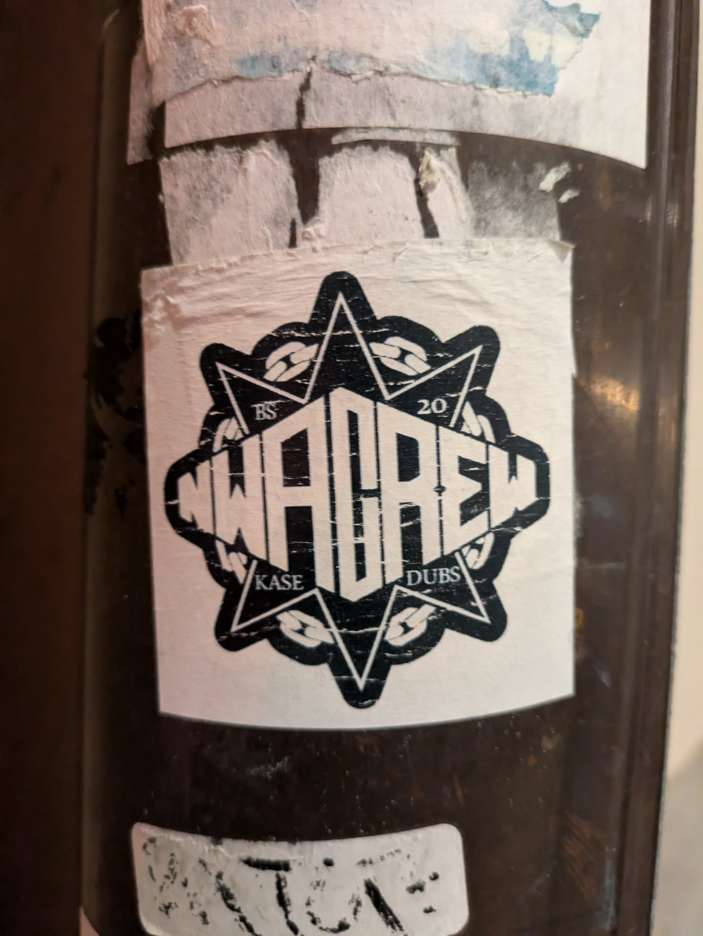 Black and white sticker with NWACREW logo. It's a star-shape design with text 'NWACREW' in the center and 'KASE' and 'DUBS' at the bottom.  The numbers 'BS' and '20' are visible on the top left and top right corners respectively. The sticker shows some signs of wear.
