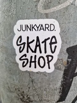 A sticker featuring the text 'Junkyard. Skate Shop'. The text 'Junkyard.' is in a smaller, sans-serif font above the text 'Skate Shop', which is written in a larger, more stylized hand-drawn font.