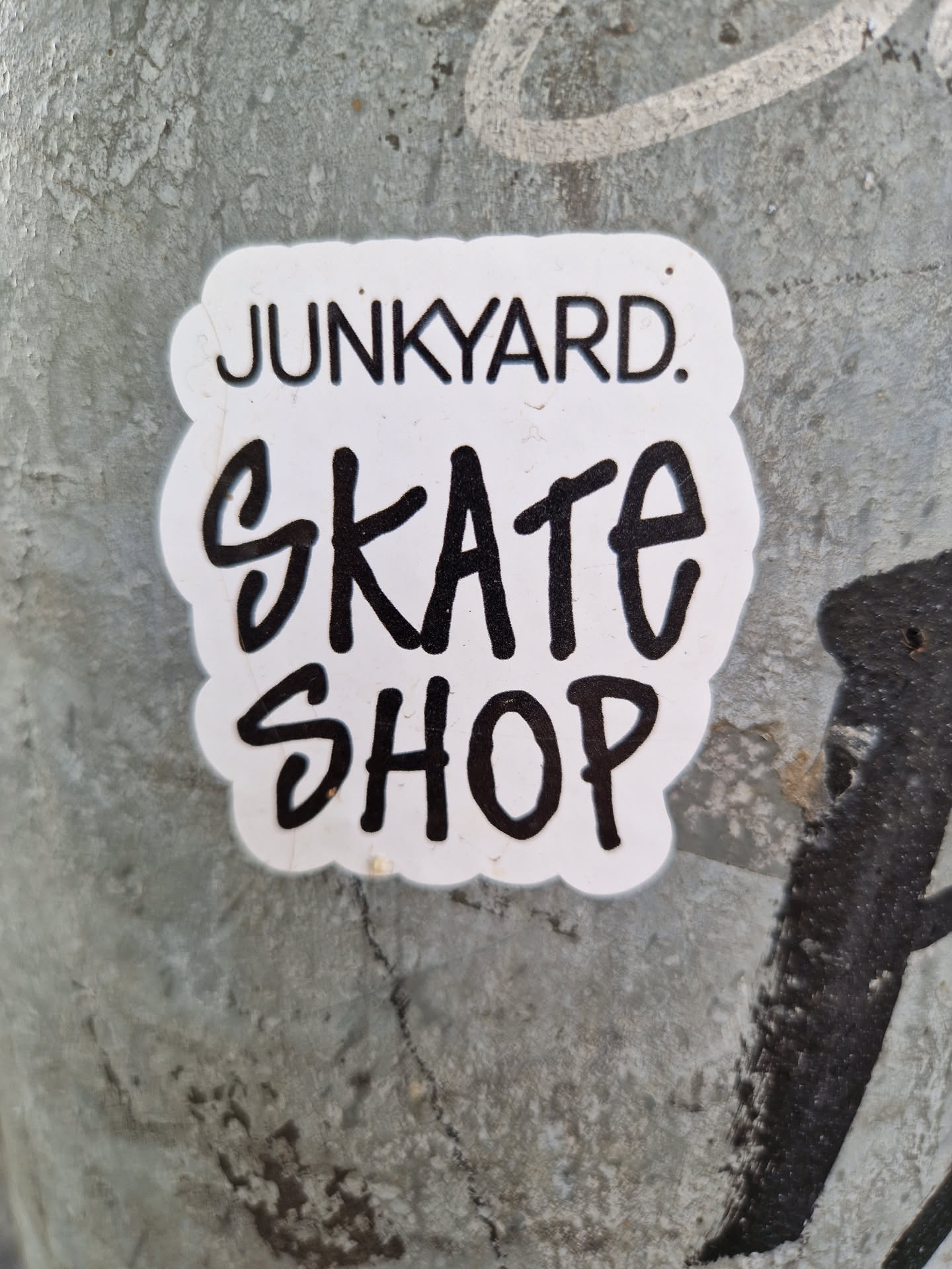 A sticker featuring the text 'Junkyard. Skate Shop'. The text 'Junkyard.' is in a smaller, sans-serif font above the text 'Skate Shop', which is written in a larger, more stylized hand-drawn font.
