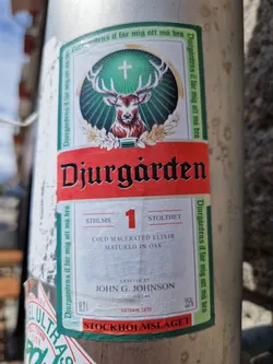 A sticker design featuring a stag and the text "Djurgården" along with other details like "Cold Macerated Elixir", "Matured in Oak", and "Stockholm Mislaget". It has a vintage look and might be associated with a drink or liquor brand.