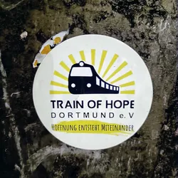 Round sticker featuring a train and sunburst design. Text includes 'Train of Hope Dortmund e.V' and 'Hoffnung entsteht miteinander'.