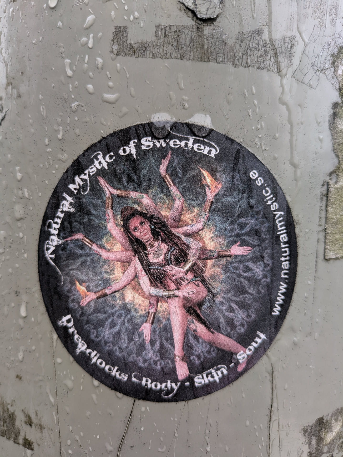 This is a round sticker with a black background featuring a woman with dreadlocks and multiple arms, reminiscent of a Hindu deity. The text around the edge of the sticker reads "Natural Mystic of Sweden", "Dreadjocks Body - Skin - Soul" and "www.naturalmystic.se".