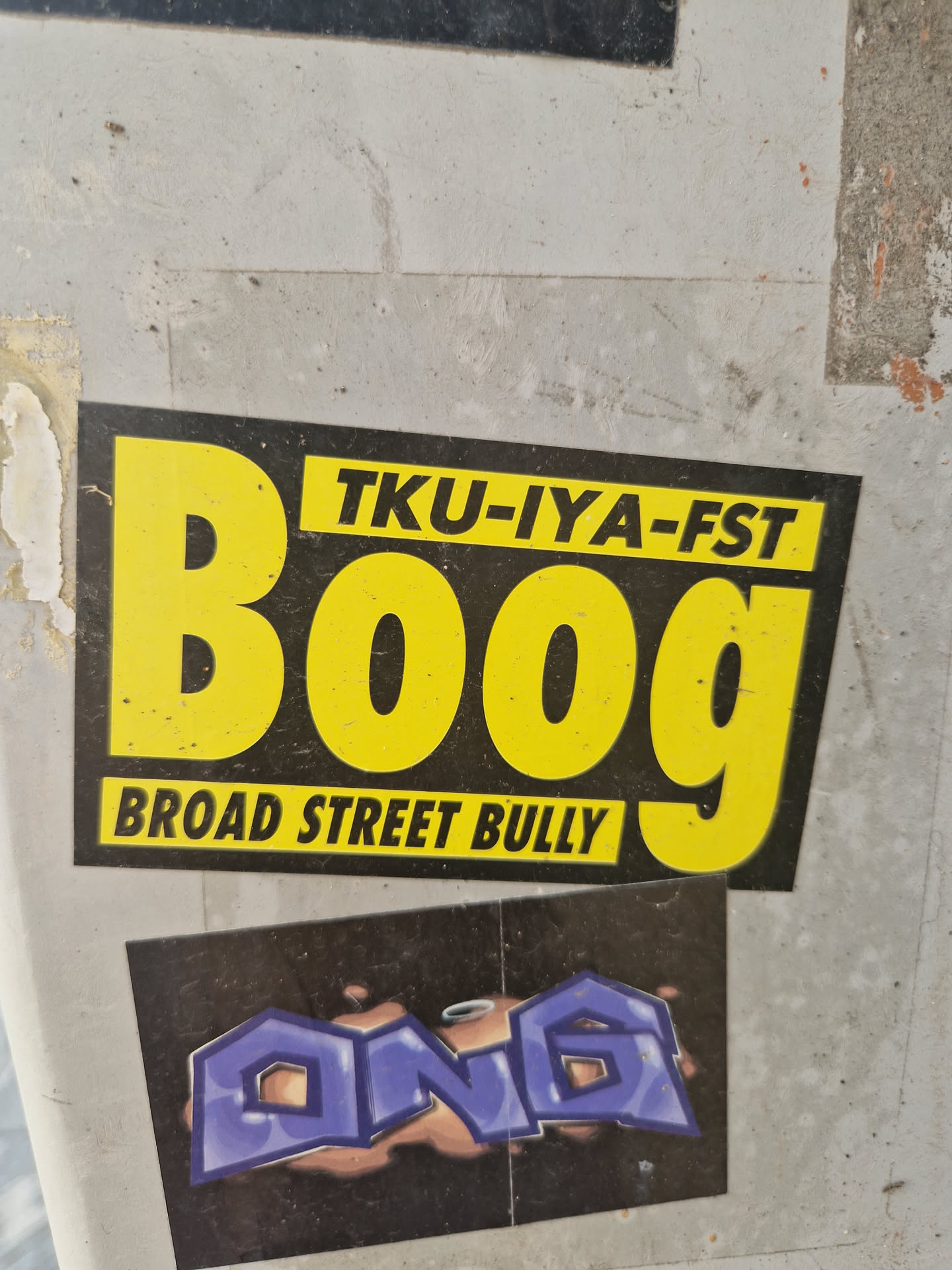 A yellow and black sticker with the text "BOOG" in large yellow letters. Above "BOOG" is the text "TKU-IYA-FST" in smaller letters. Below "BOOG" is the text "BROAD STREET BULLY".