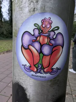 Street sticker A round sticker featuring a stylized female figure in a vibrant color palette of purples, reds, and greens. The figure is depicted in a seated position, with a unique, almost alien-like aesthetic. The artist's signature is visible at the bottom.