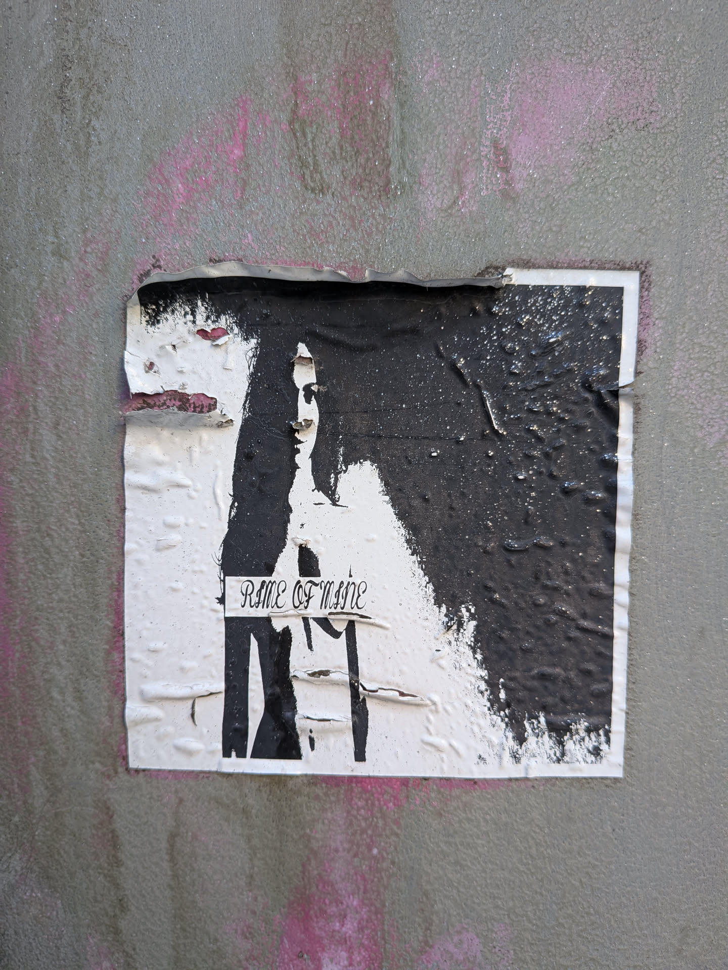 The sticker is predominantly white with a large, irregular patch of thick, black paint obscuring the right side and top. A ghostly, black silhouette of a face and upper torso is visible on the white portion, with the black paint appearing to drip and splatter. The text 'RIME OF MNNE' is written in a gothic-style font across the lower center of the white area. The sticker is wrinkled and torn, particularly along the top edge, revealing underlying paper and some pink spray paint on the wall behind. The texture of the black paint is uneven and appears somewhat glossy in places.