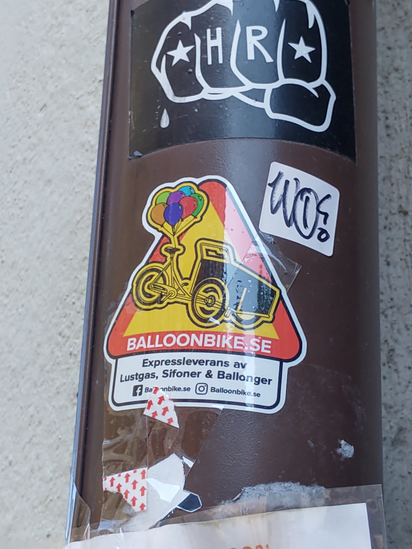 Sticker featuring a bicycle carrying colorful balloons.  The sticker is a triangular warning sign with the website address and a short description of the business.