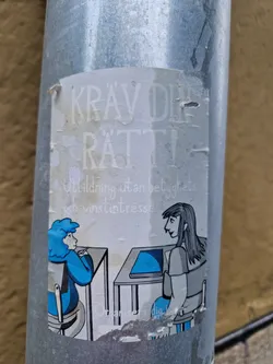 A sticker with an illustration of two people sitting at desks in a classroom. The text on the sticker says "Krav dr ratti" and "Utbildning utan betyg och vinstintresse".