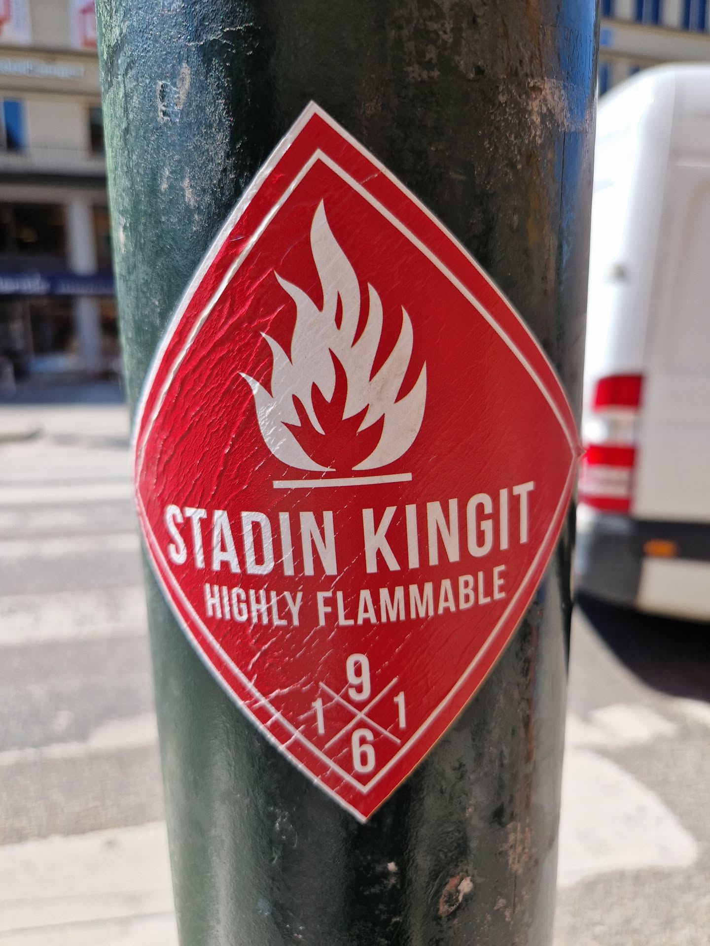 Red diamond-shaped sticker with a flame symbol and the text "Stadin Kingit" and "Highly Flammable". There are also numbers 1961 arranged in a cross within the diamond shape.