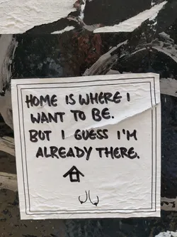 A minimalist sticker with a handwritten quote. The sticker has a black border and features a small house symbol and a unique symbol at the bottom.