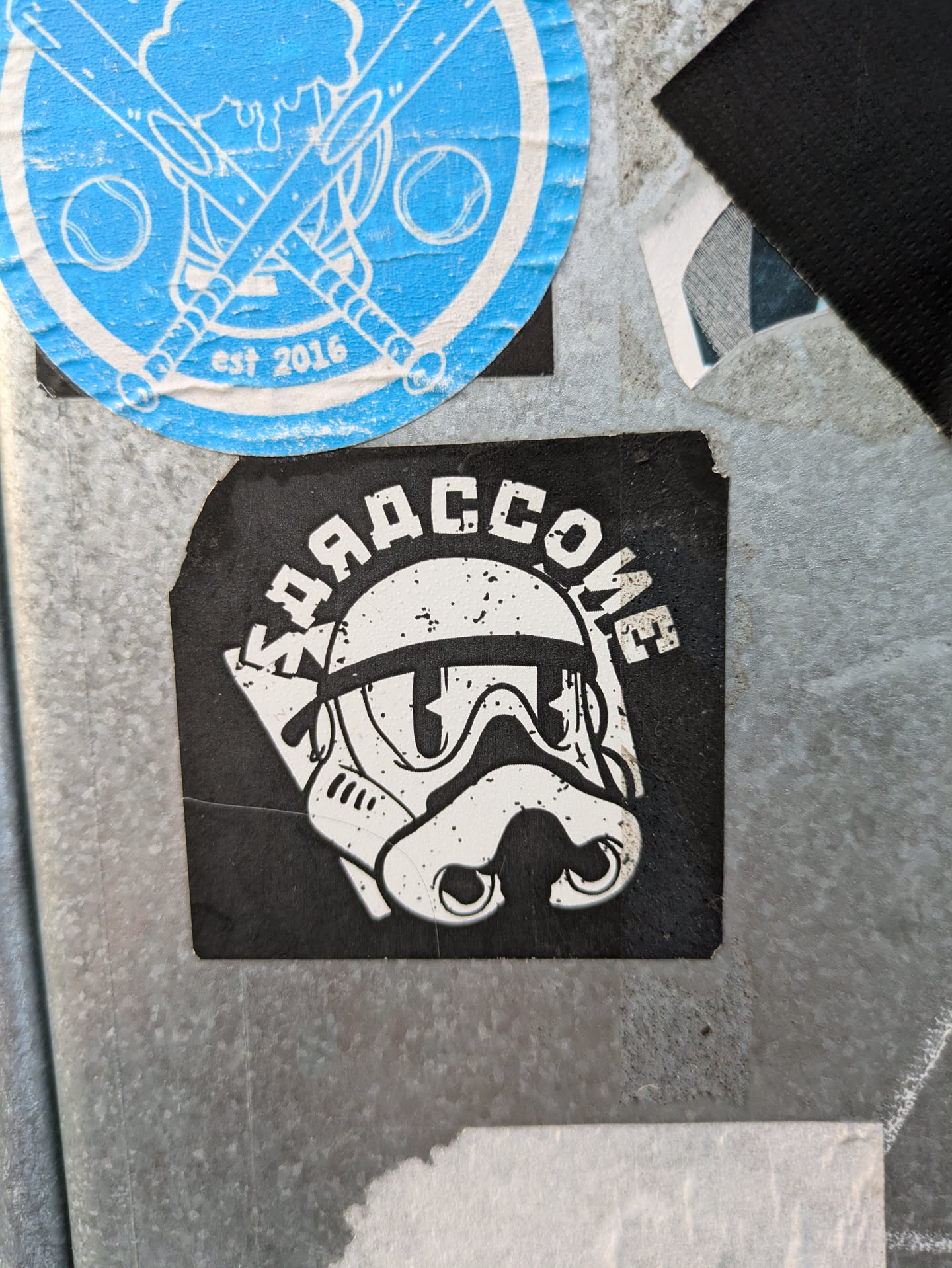 A black and white sticker featuring a distressed illustration of a Star Wars stormtrooper helmet with the word "SARLACCONE" written in a stylized font around it.