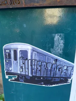 Sticker depicting a subway train with graffiti-style lettering that says "SILVER AGE". The train appears to be a vintage model, adding to the retro aesthetic. The sticker is affixed to a teal-colored surface.