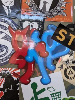 A sticker featuring two cartoon devil characters, one red and one blue, with a dripping paint style.  The characters have horns and a mischievous expression.