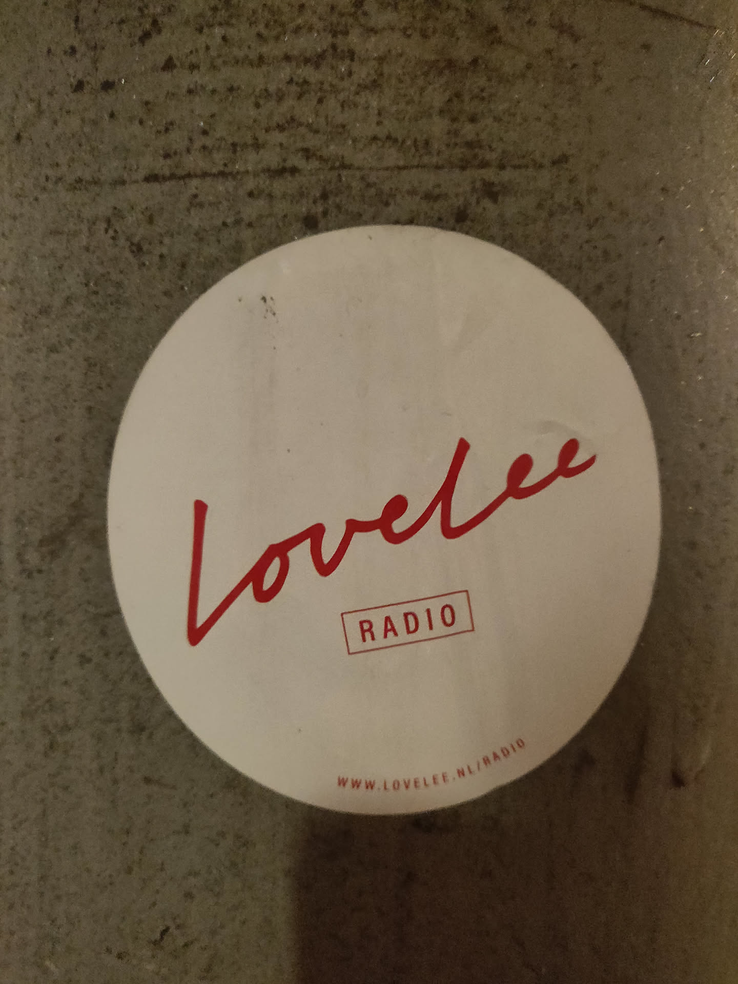 Round white sticker with red text.  The main text says "Lovelee" in a stylized script font, with the word "RADIO" underneath in a sans-serif font.  A URL is printed at the bottom.