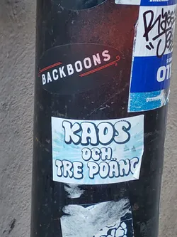 A sticker with the text "KAOS OCH TRE POÄNG" which translates to "Chaos and three points" in Swedish. The text is stylized in a retro, cartoonish font with a light blue background. 