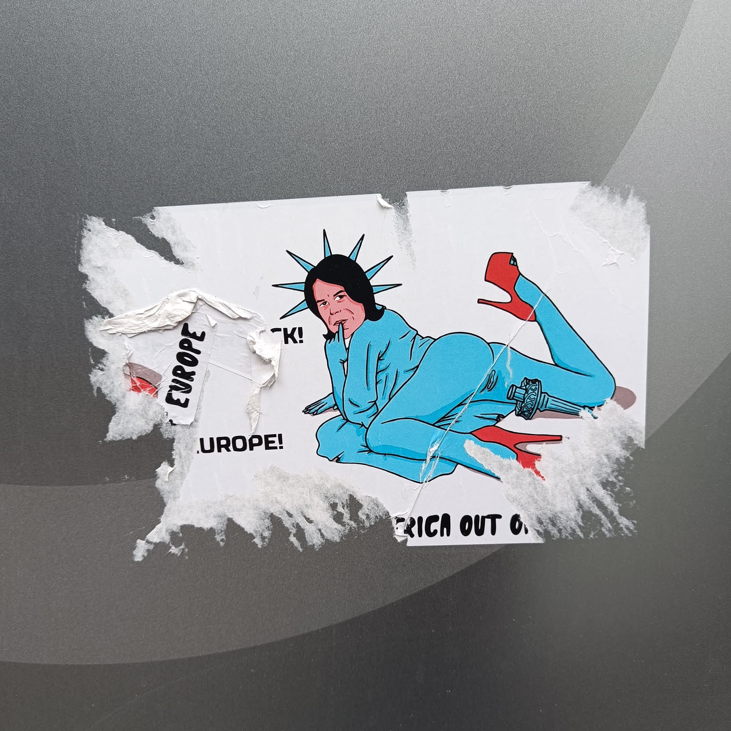 A sticker depicting a stylized Lady Liberty figure in a suggestive pose, with the text "Europe!" visible on a torn portion of the sticker.  The bottom of the sticker is partially obscured but shows the phrase "rica out o...". The artwork is bold and uses a cartoonish style.
