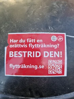 Red sticker with text in Swedish.  It asks if you've received an unfair moving invoice and urges you to contest it.  It also includes a QR code and a website address.