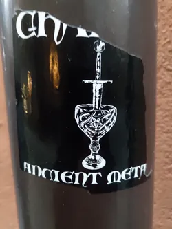 Black and white sticker with a goblet and a sword. The text "Ancient Metal" is visible at the bottom. 
