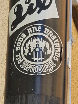 Black and white circular sticker with a design depicting a burning building with religious symbols, surrounded by text that says "Gods Are Bastards".