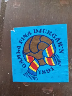 A sticker featuring Djurgårdens IF's logo, a soccer ball with a scarf in the club's colors. The year 1891 is visible, indicating the club's founding year. The sticker is blue and features the text "Gefle fina Djurgården 1891".