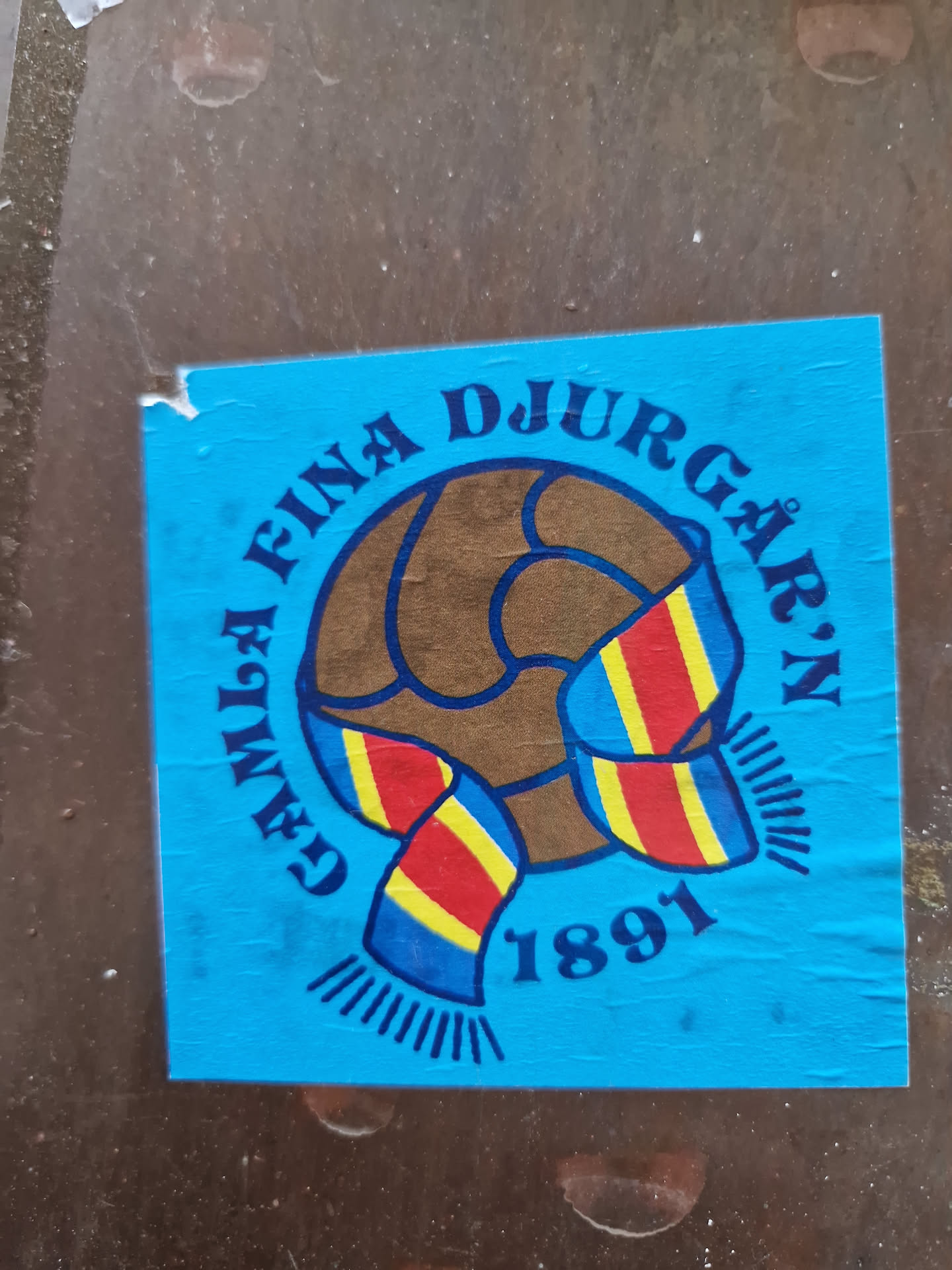 A sticker featuring Djurgårdens IF's logo, a soccer ball with a scarf in the club's colors. The year 1891 is visible, indicating the club's founding year. The sticker is blue and features the text "Gefle fina Djurgården 1891".